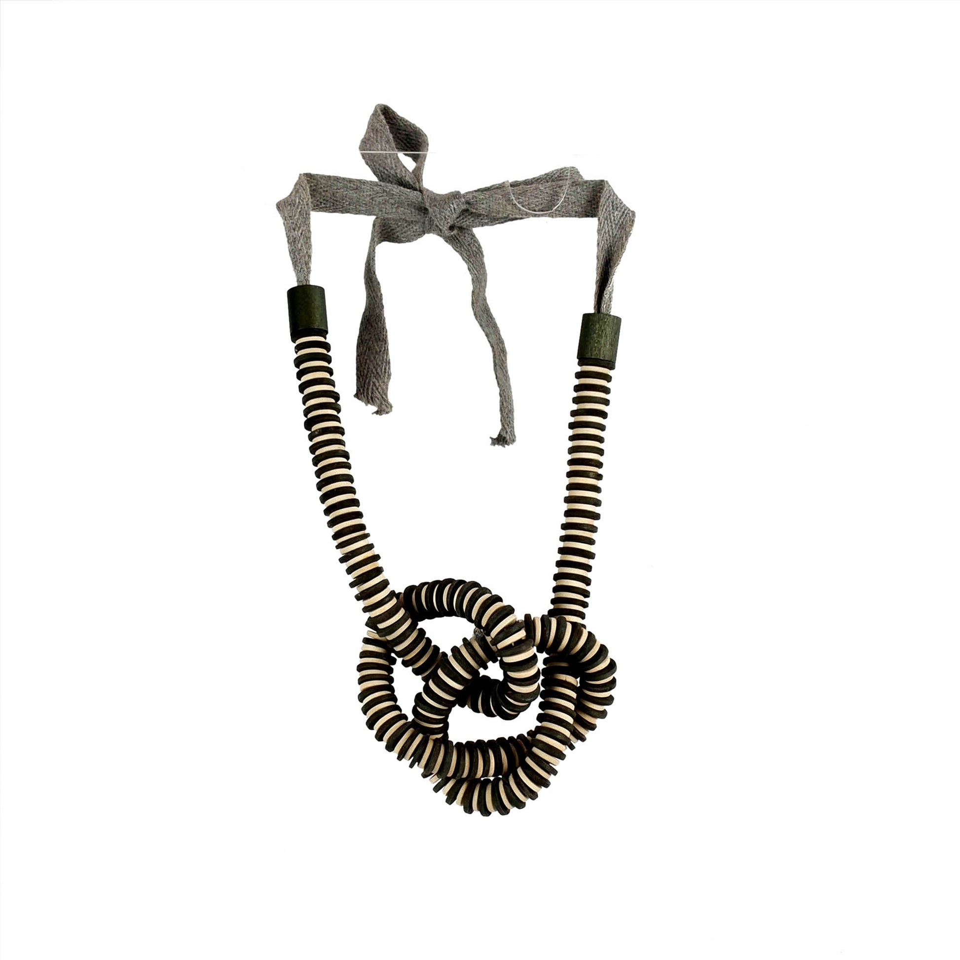 Handmade black and white wooden necklace featuring a knotted pendant and grosgrain ribbon neckline. Ethically crafted by a sustainable fashion accessories manufacturer.